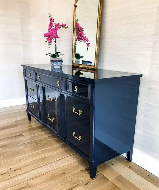 a navy lacquered sideboard with chic fixtures, a potted orchid and a mirror is a lovely addition