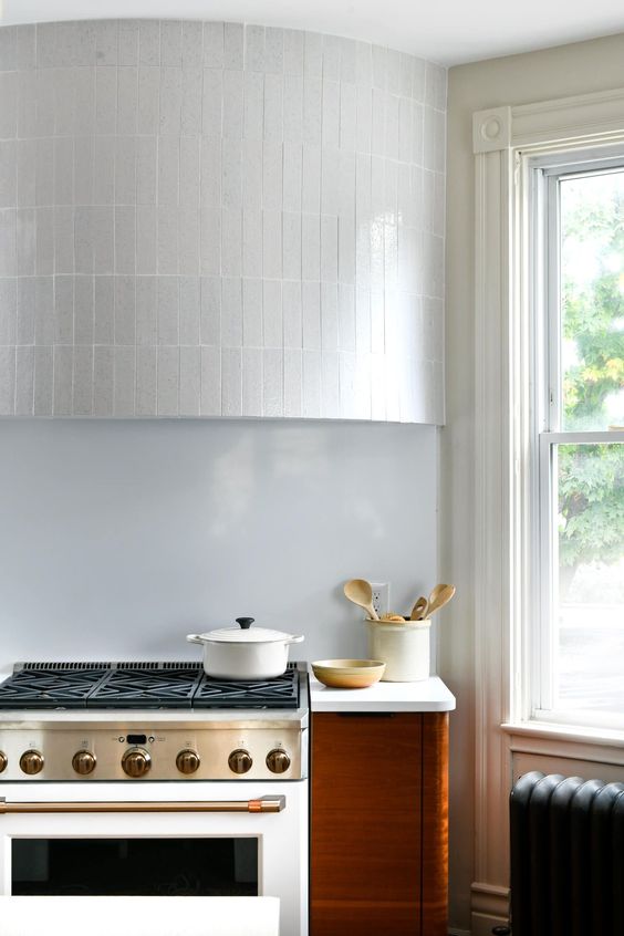 an accented rounded hood clad with white stacked tiles is a cool and catchy idea for a modern kitchen