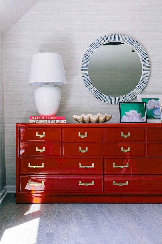 a gorgeous red lacquer dresser with gold handles is a bold statement for any room