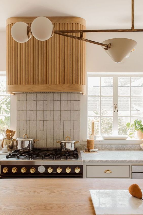 a modern neutral kitchen with a fluted hood and a stacked tile backsplash is a stylish and lovely space