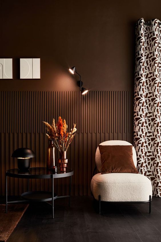 a refined chocolate brown space with fluting, a creamy boucle chair, a black coffee table and some lamps