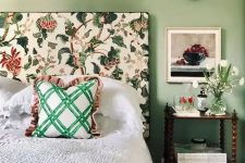 26 a cool and chic bedroom with green walls, a bed with a floral headboard, neutral bedding and a green bedspread, a nightstand and white blooms