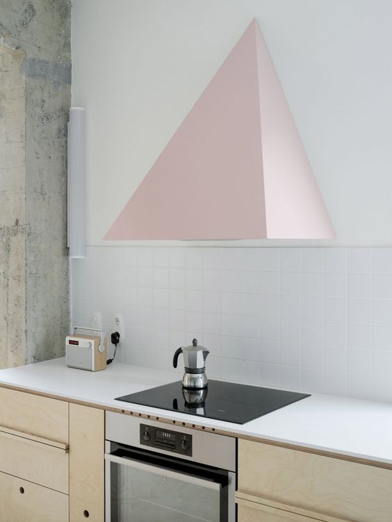 a modern neutral kitchen with white countertops, a white square tile backsplash and a pink geometric hood that is wow