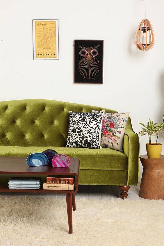 an eclectic living room with a chartreuse tufted sofa, a stained coffee table, a gallery wall and a pendant lamp