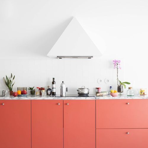 a coral kitchen with a white stone countertop and a white geometric hood is a stylish and catchy space