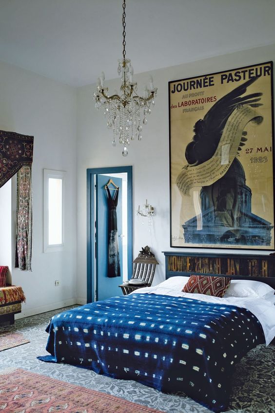 an eclectic bedroom with a dark-stained bed and printed bedding, patterned rugs and curtains and a large poster