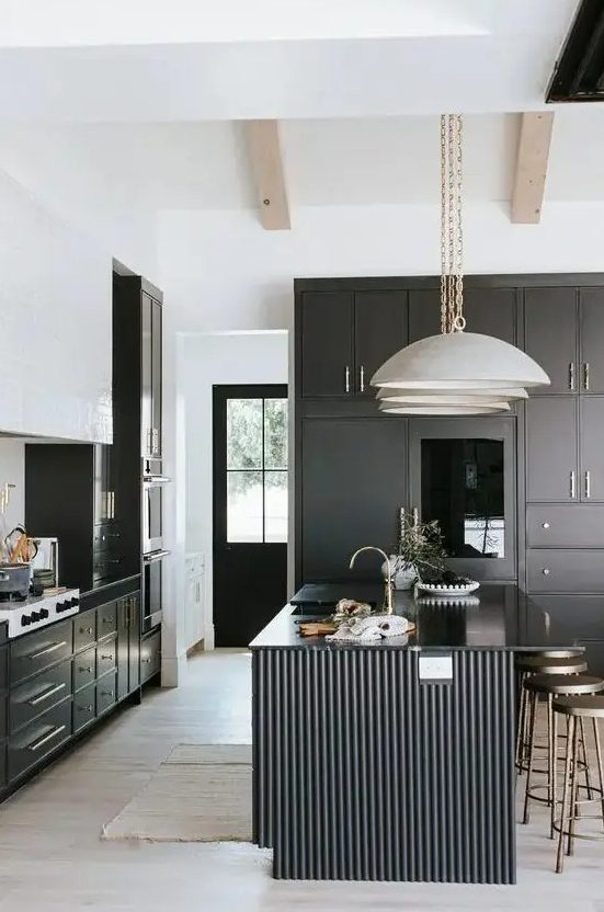 a modern black and white kitchen with black cabinetry, a white tile hood and a black fluted kitchen island with glossy countertops