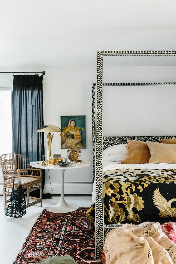 an eye-catchy bedroom with a printed bed and bedding, printed rugs, art, a rattan chair and some pillows