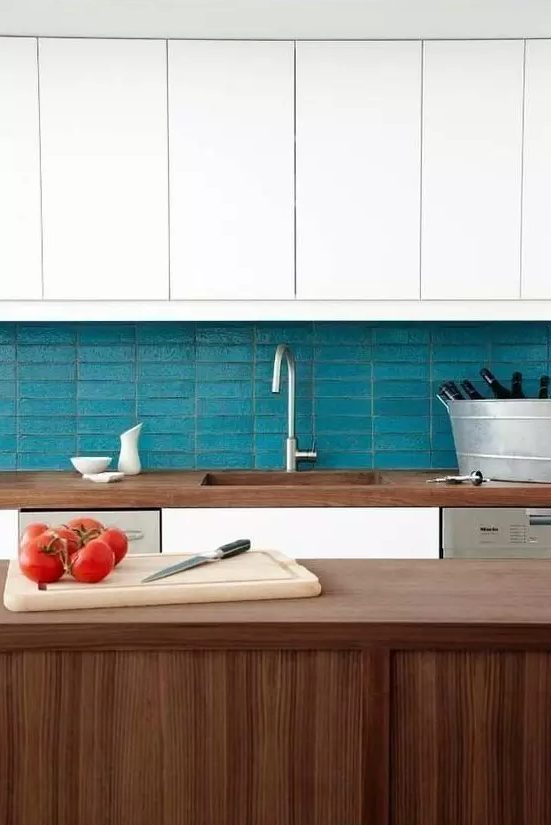 a chic kitchen in white and stained wood, with a blue stacked tile backsplash is very stylish
