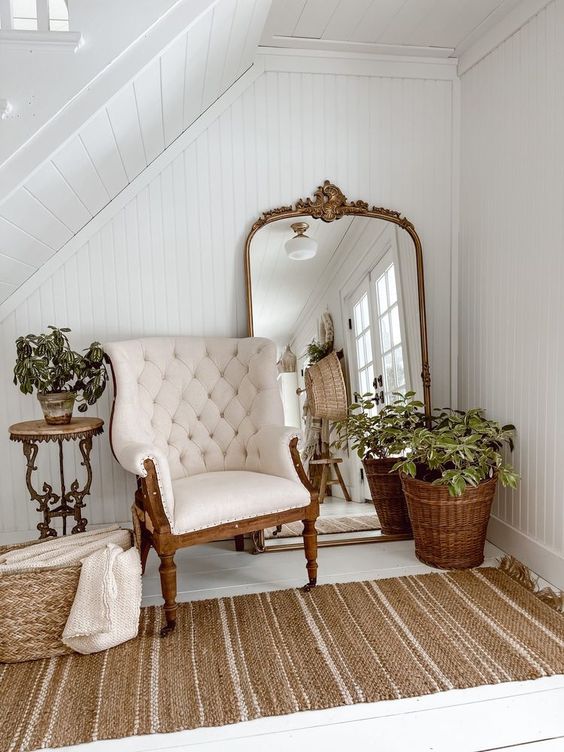a beautiful under the stairs nook with a mirror in a frame, a vintage chair, greenery and baskets is a lovely space