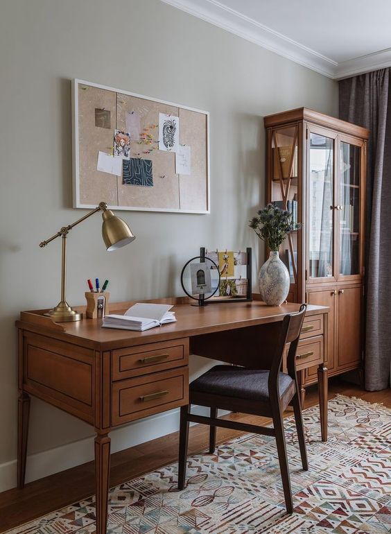 a rich-stained vintage desk and a dark-stained chair plus a glass armoire create a chic home work space