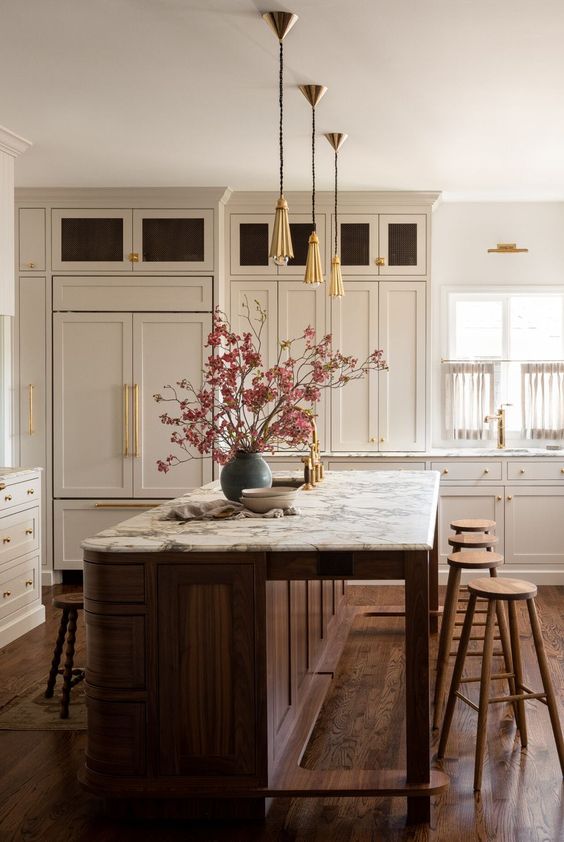 a stylish warm neutral kitchen with creamy shaker cabinets, a rich-stained kitchen island and stained stools
