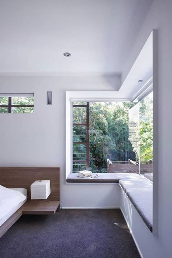a bedroom features two partly glazed walls and an upholstered window sill as a daybed
