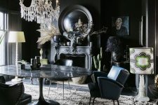 a Gothic dining room with black walls and a ceiling, a vintage fireplace, a large table and navy chairs, a crystal chandelier