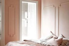 a Peach Fuzz bedroom with paneling, a low bed with peachy and blush bedding, a sphere pendant lamp