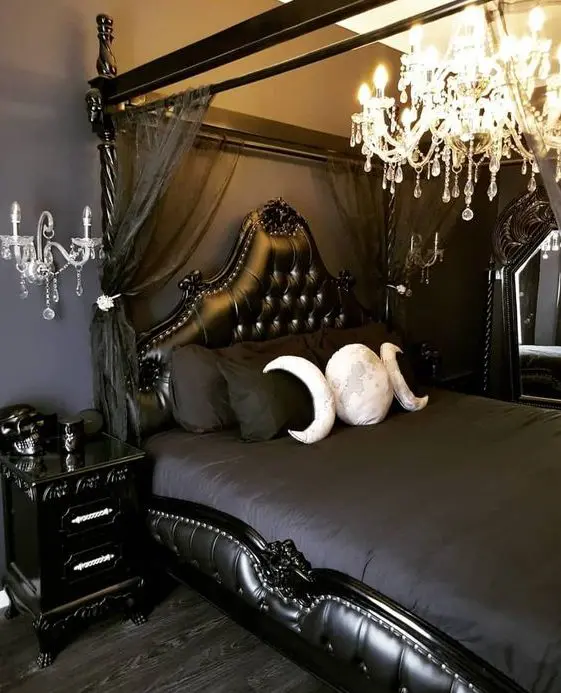 a beautiful Gothic bedroom with black walls, refined furniture, dark bedding, a crystal chandelier and wall sconces