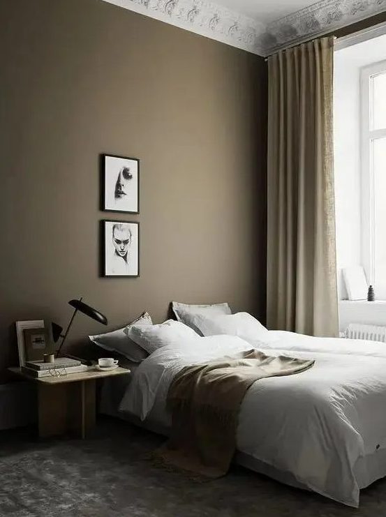 a beautiful Scandi bedroom with a taupe accent wall, a bed, a light-stained nightstand, a mini gallery wall and tan and gold touches