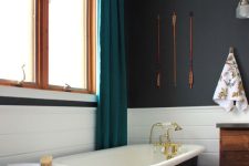 a beautiful bathroom with soot walls, white tile, a black free-standing bathtub, a stool, a stained vanity and teal curtains