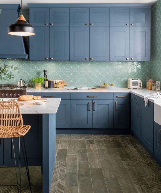a beautiful blue kitchen with white stone countertops and a green fishscale tile backsplash