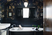 a beautiful modern Goth bathroom with black and gold wallpaper, black fluting, a tile floor, a black tub and a white sink