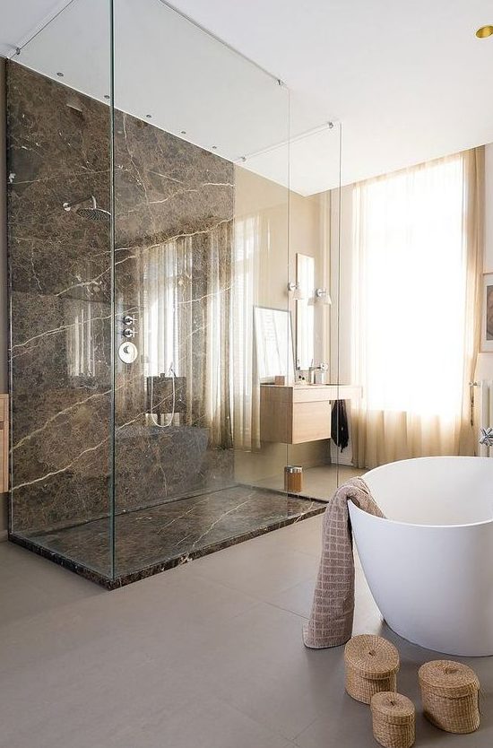 a beautiful neutral bathroom with a gorgeous brown marble shower, an oval tub, a floating sink and baskets for storage