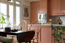 a beautiful peachy pink kitchen with a kitchen island and built-in appliances plus a dining zone with a folding table