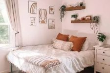 a boho teen bedroom with a metal bed, a gallery wall, wall-mounted shelves, a white dresser, potted greenery and neutral textiles
