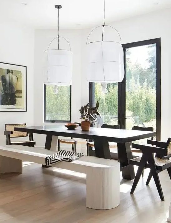 A bold dining zone with a view, a dark stained dining table and chairs, a whitewashed bench and a light stained floor