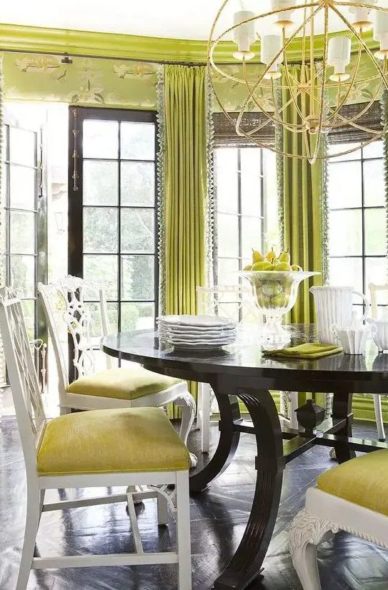 a bold eclectic dining room with chartreuse printed walls and curtains, a dark table and yellow chairs plus a statement chandelier