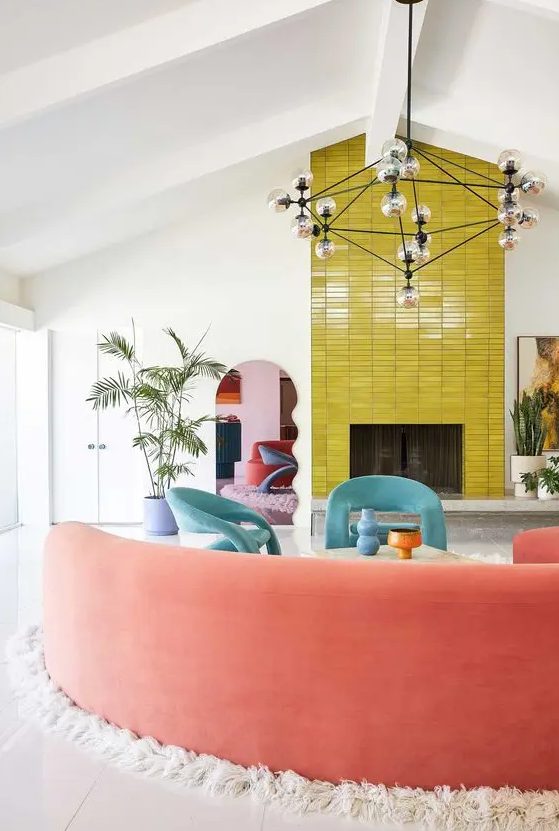 a bold living room with a fireplace clad with chartreuse stacked tiles, blue chairs, a coral rounded sofa and potted plants