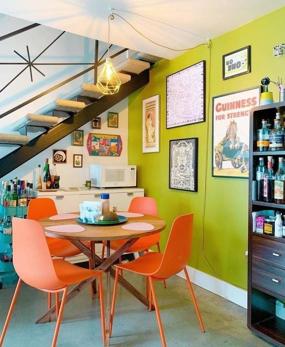 a bold nook with a chartreuse wall, a stained table and coral chairs, a gallery wall, a home bar and a storage unit