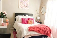 a bright and cool modern teen girl room with black furniture, pink textiles, an artwork, gold butterflies and a mirror plus some blooms