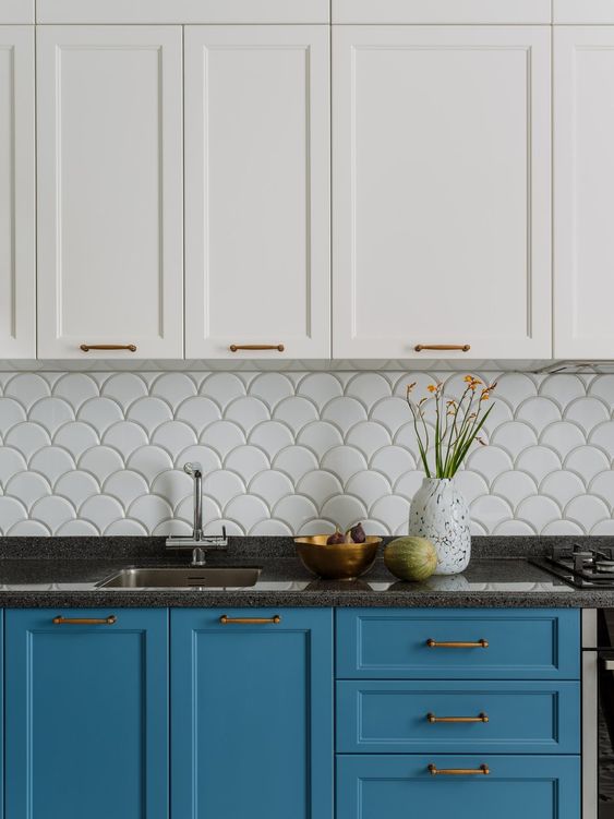 a bright blue and white kitchen with shaker cabinets, black countertops, a white scallop tile backsplash is catchy and cool