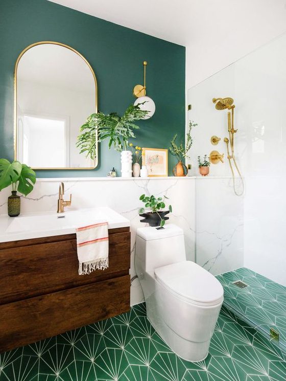 a bright mid-century modern bathroom with a green wall and a green mosaic tile floor, a dark stained vanity, gold fixtures and white appliances