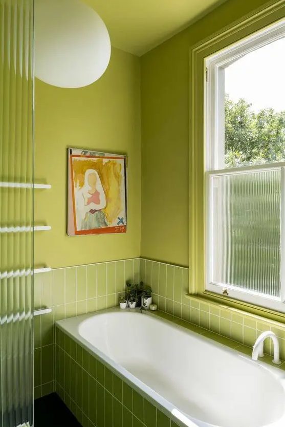 a chartreuse bathroom with stacked skinny tiles, a window covered for privacy and some art is extra bold and wow