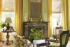 a chartreuse living room with a black fireplace, green and printed floral chairs, an ottoman and elegant tables with lamps
