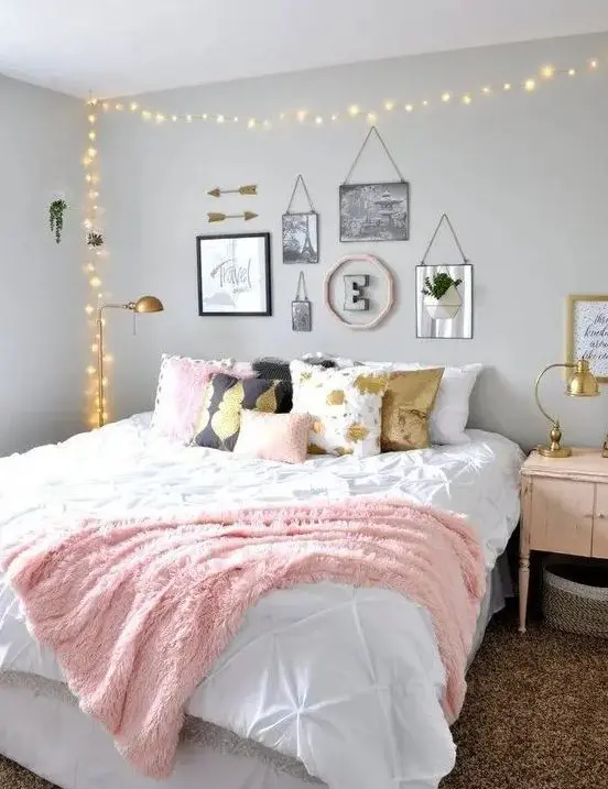 a chic teen girl bedroom with grey walls, a large bed with printed pillows, a lovely gallery wall and lights over the bed