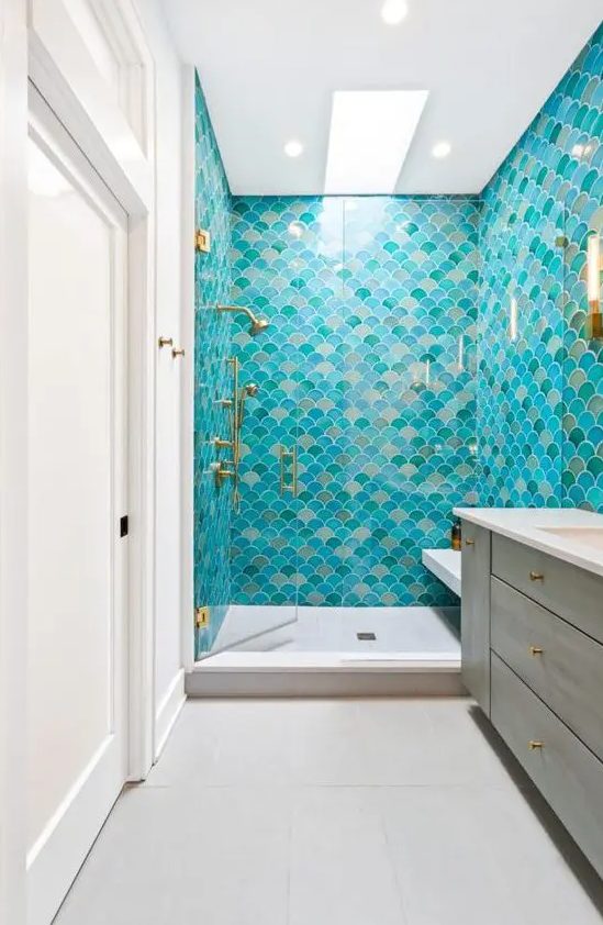 a colorful mermaid bathroom decorated with bright fishscale tiles, a wooden vanity and touches of gold is chic
