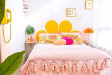 a colorful modern teen bedroom with a bed and pink and yellow bedding, a bench, a basket and artwork