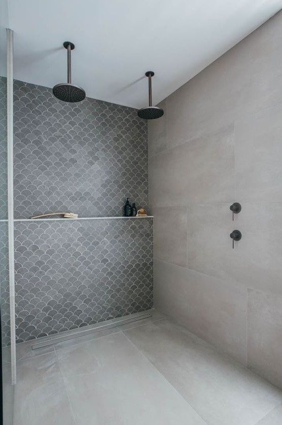 a contemporary shower space done with large scale stone tile and grey fish scale tile plus a shelf for everything necessary