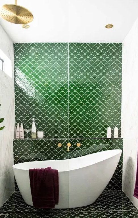 a cool bathroom with white marble and green fishscale tiles, a tub in the shower space and gold fixtures is chic and cool