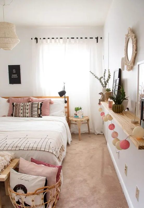 a cool boho teen bedroom with an open shelf that features decor and greenery, a wooden bed, a bench and a rattan basket