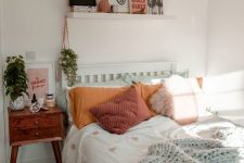 a cool modern teen bedroom with a bed and colored bedding, a stained nightstand, a ledge gallery wall and plants