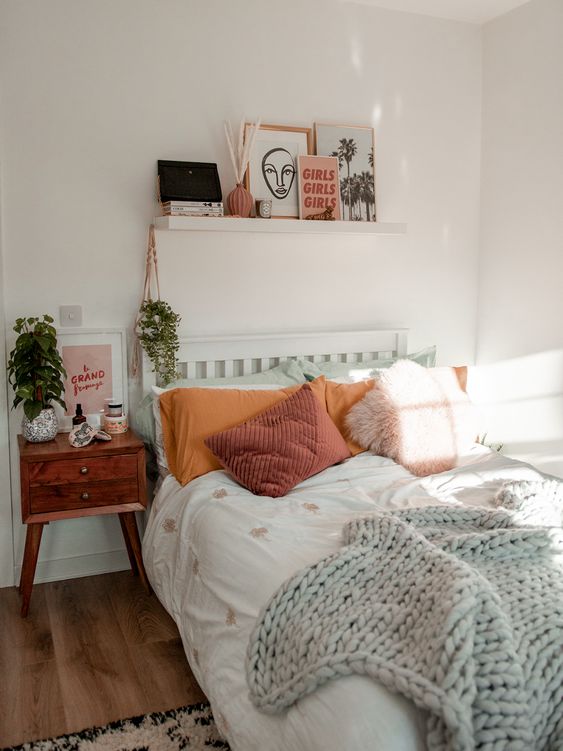 a cool modern teen bedroom with a bed and colored bedding, a stained nightstand, a ledge gallery wall and plants