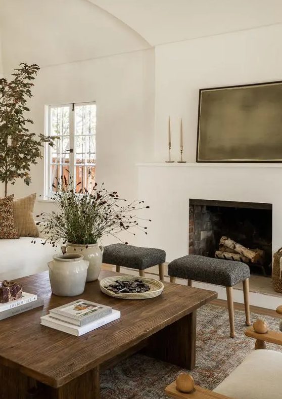 a cozy earthy living room with a fireplace, a stained coffee table, neutral seating furniture and potted plants