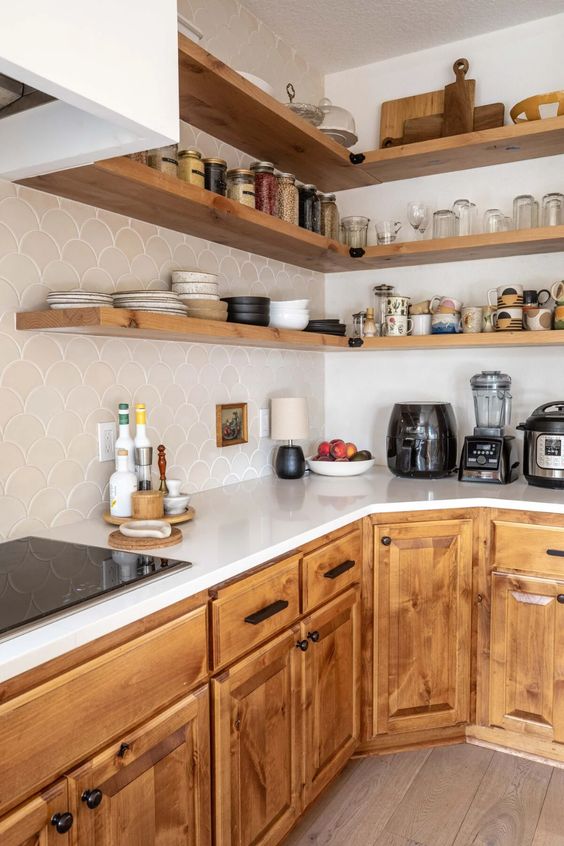 a cozy light-stained kitchen with ivory fish scale tiles and open shelves is a cool and welcoming space to be in