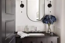 a dark-stained bathroom vanity with multiple drawers, an oval mirror and sconces is a cool idea to add a refined touch to the space