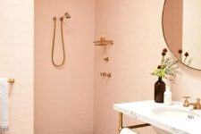 a delicate peachy pink bathroom clad with tiles, a terrazzo floor, a free-standing sink and a round mirror is very soft