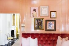 a glam living room with Peach Fuzz walls and a ceiling, a burgundy tufted sectional, a crystal chandelier and a gallery wall