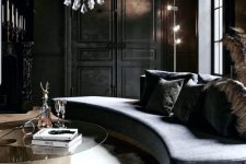 a gorgeous refined living room in goth style, with soot walls, a grey curved sofa, a crystal chandelier and a glass table
